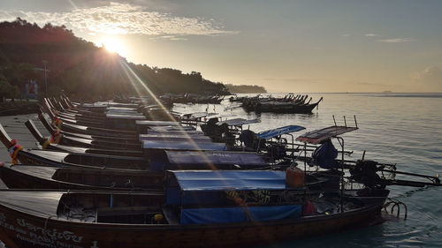 Boats moored in sea against sky during sunset