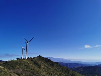 Wind turbines on landscape against sky