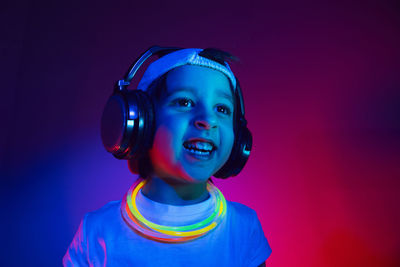 Cyberpunk boy child in a white t shirt and large headphones listening to music on the background 