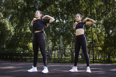 Mom and daughter in sportswear on a sunny summer day on the embankment in the park