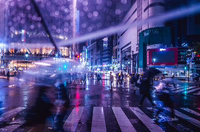 People walking on wet street at night