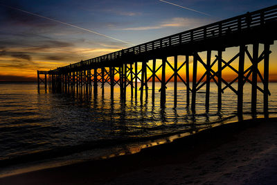 Silhouette pier over sea against sky during sunset