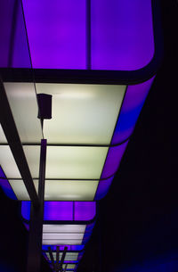 Low angle view of illuminated lamp against wall at night