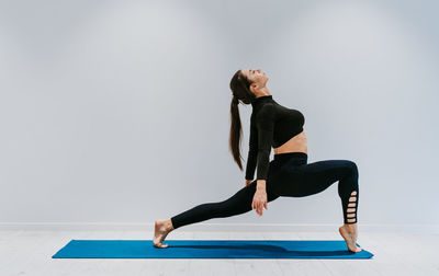 Full length of woman stretching against white background