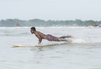 Side view of man splashing water in sea