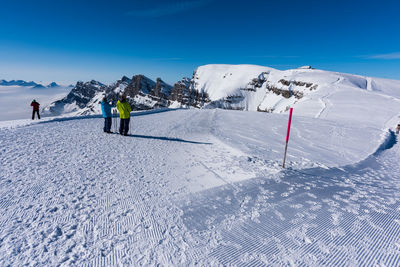 People skiing on snowcapped mountain against sky