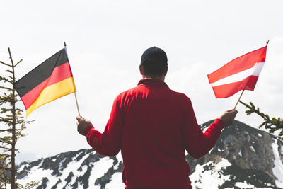 Rear view of man holding flag against clear sky