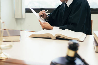 Midsection of woman reading book at table