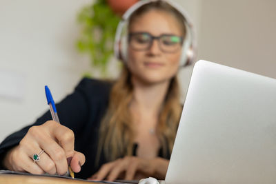 Woman working at home with laptop and papers on desk and headphones. home office . gray notebook 