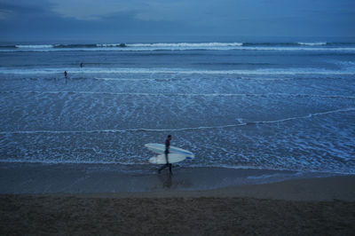 High angle view of men walking on shore at beach against sky