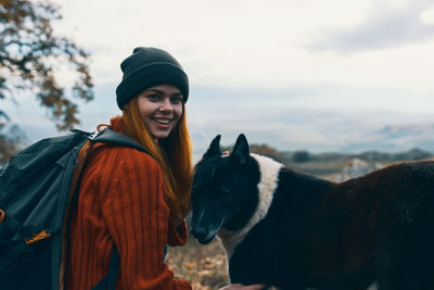 Portrait of young woman with dog against sky