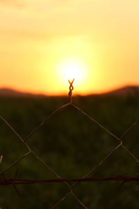 Close-up of barbed wire fence against sky during sunset