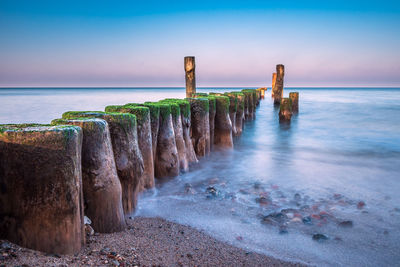 Wooden posts on beach against sky