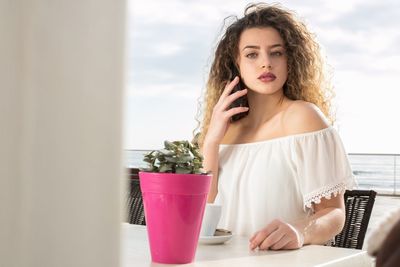 Portrait of beautiful woman talking on mobile phone at table in cafe