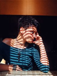 Young woman looking away while sitting on table at home