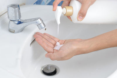Close-up of man washing hands in sink