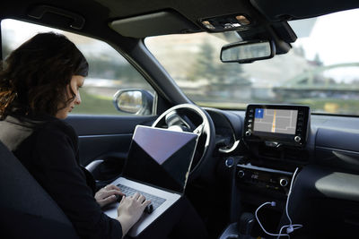 Businesswoman with laptop working in driverless car