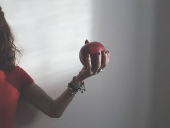 Close-up of woman holding apple against wall