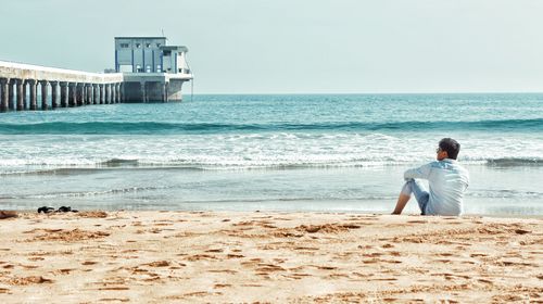 Rear view of man looking at sea against sky