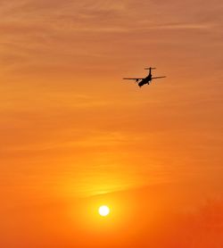 Low angle view of silhouette airplane against sky during sunset