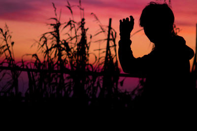 Silhouette woman by lake against sky during sunset