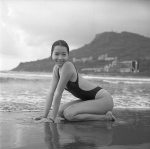 Portrait of young woman on beach against sky