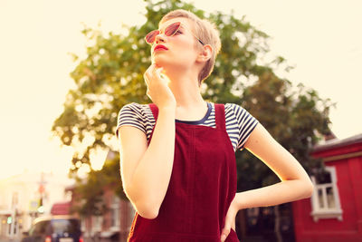 Young woman looking away while standing against blurred background