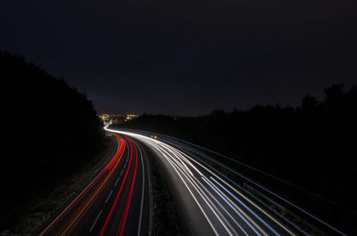 Light trails on highway against sky at night