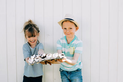 Siblings holding up their egg shells that they planted seeds into