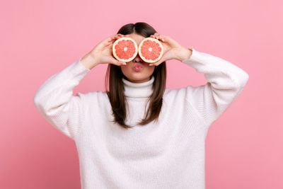 Midsection of woman holding camera against yellow background