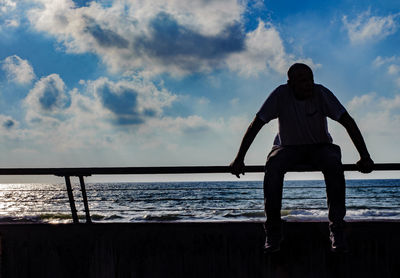 Rear view of man looking at sea against sky