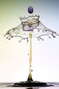 Close-up of water drop on table against white background