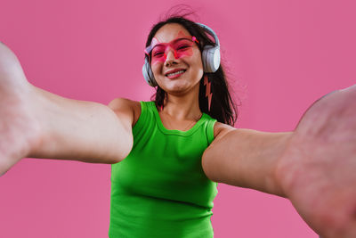 Portrait of young woman standing against yellow background
