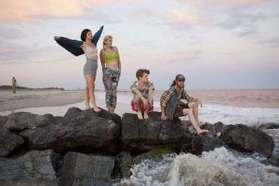 People on rock at beach against sky