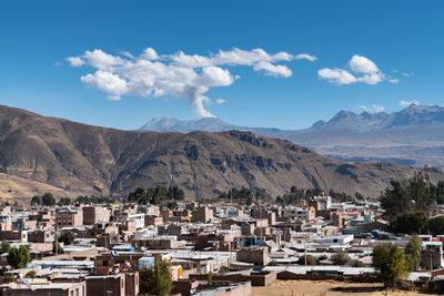 Scenic view across the town of chivay, peru to the  sabancaya volcano erupting ash into the sky