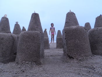 Full length of girl standing by sandcastles at beach