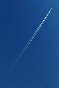 Low angle view of vapor trails in blue sky
