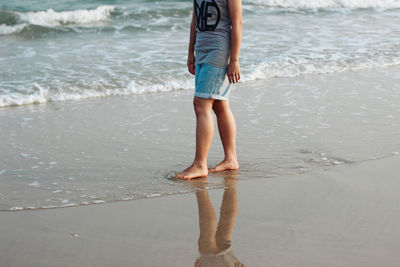 Low section of man standing on beach