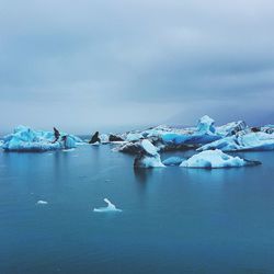 Scenic view of icebergs in sea against sky