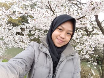 Portrait of smiling young woman standing against blue sky