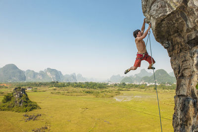 Male climber pulling up on overhanging rock in yangshuo / china