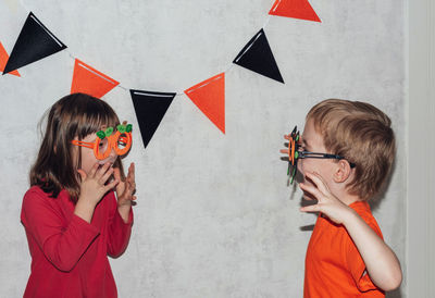 Children in carnival masks play and scare each other.a boy in a spider mask scares a girl, she smile