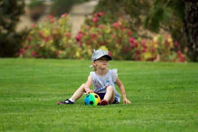 Cute boy playing with ball on grass