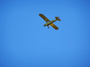 Low angle view of airplane against clear blue sky