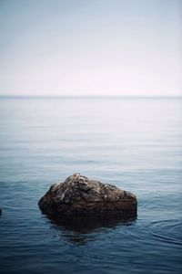 Rocks in sea against clear sky