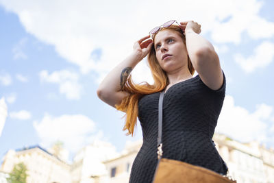Young woman copper hair is wearing fashion sunglasses in a blue sky