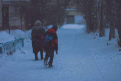 Rear view of people walking on snow covered city during winter