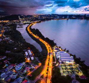 High angle view of illuminated city by buildings at night