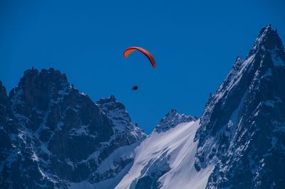 Person paragliding over snowcapped mountain