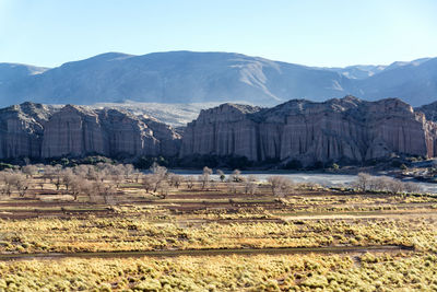 Scenic view of cliffs and mountain against clear sky